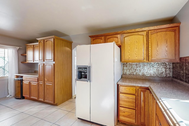 kitchen with light tile patterned floors, sink, white refrigerator with ice dispenser, and tasteful backsplash