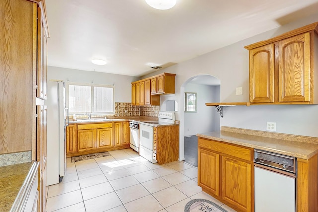 kitchen featuring light tile patterned flooring, sink, white appliances, and decorative backsplash