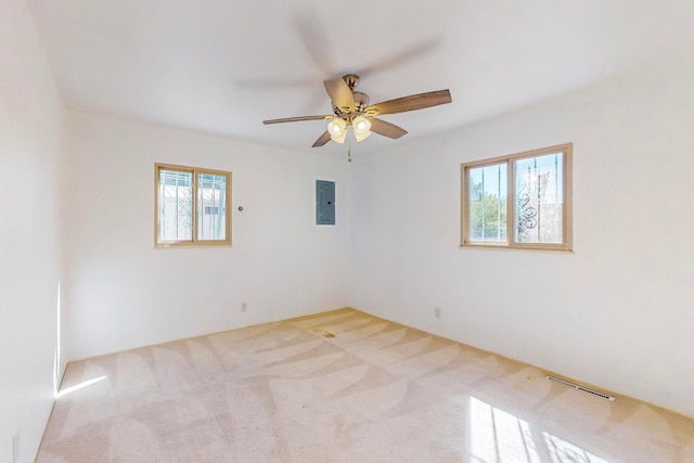 carpeted spare room with electric panel, ceiling fan, and plenty of natural light