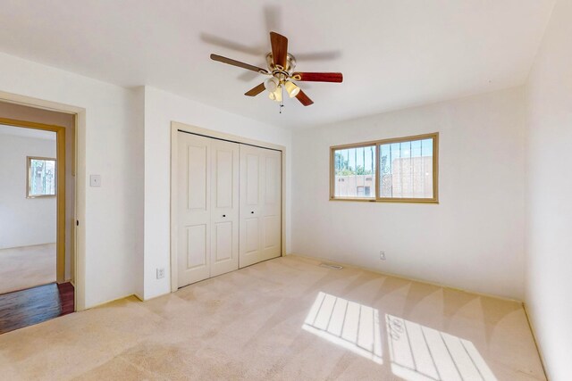 unfurnished bedroom with a closet, ceiling fan, and light colored carpet