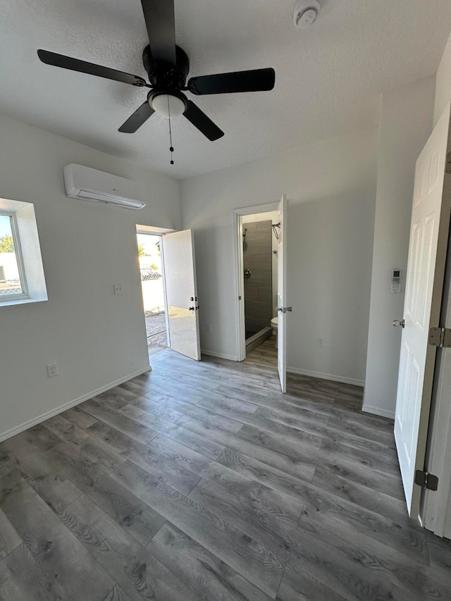 unfurnished bedroom featuring an AC wall unit, ceiling fan, dark wood-type flooring, and a textured ceiling