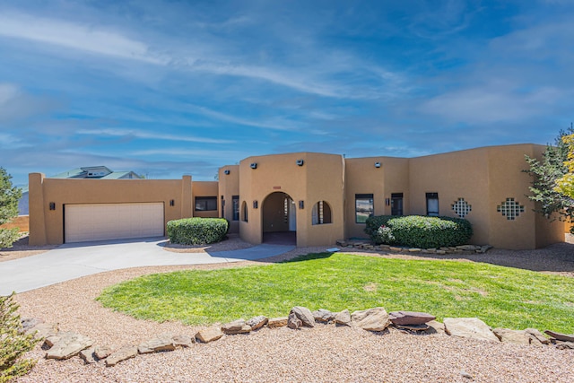 pueblo-style home with a front yard and a garage