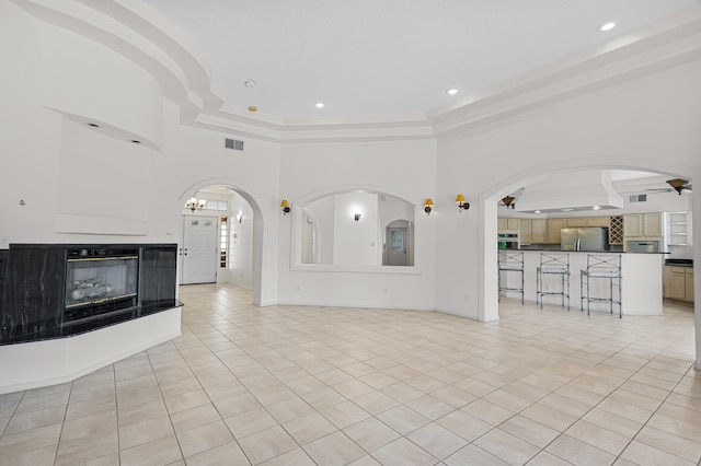 unfurnished living room featuring a raised ceiling, light tile patterned flooring, a towering ceiling, and ceiling fan