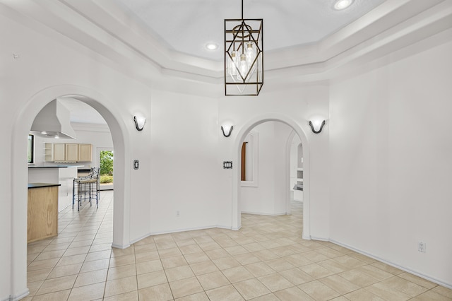 tiled empty room featuring a raised ceiling and ornamental molding