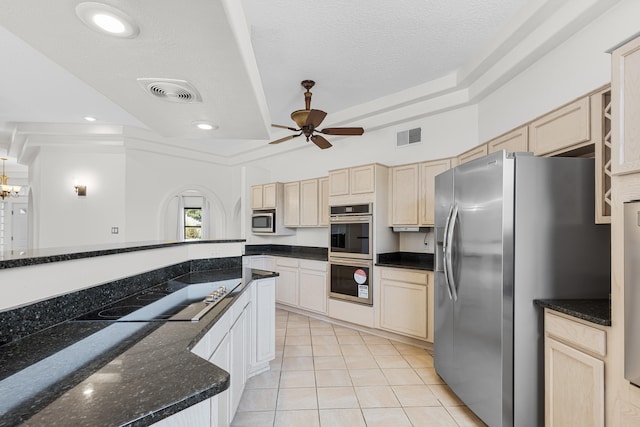 kitchen featuring appliances with stainless steel finishes, ceiling fan with notable chandelier, light tile patterned flooring, and dark stone counters