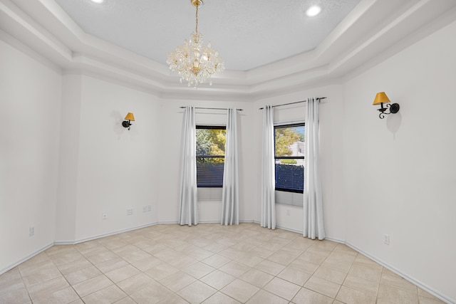 unfurnished room with an inviting chandelier, a tray ceiling, and light tile patterned floors