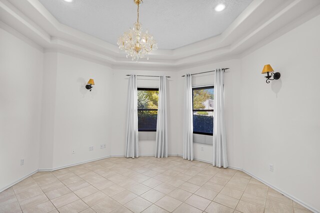 1220 Mesa Ridge Dr SW, Los Lunas, NM 87031 - spare room featuring a raised ceiling, a chandelier, and light tile patterned floors