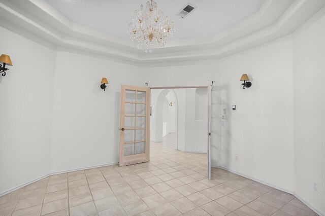 1220 Mesa Ridge Dr SW, Los Lunas, NM 87031 - unfurnished room with arched walkways, a tray ceiling, a chandelier, and light tile patterned flooring