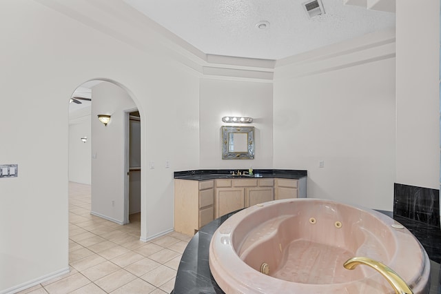 bathroom with vanity, a tub to relax in, tile patterned flooring, and a textured ceiling