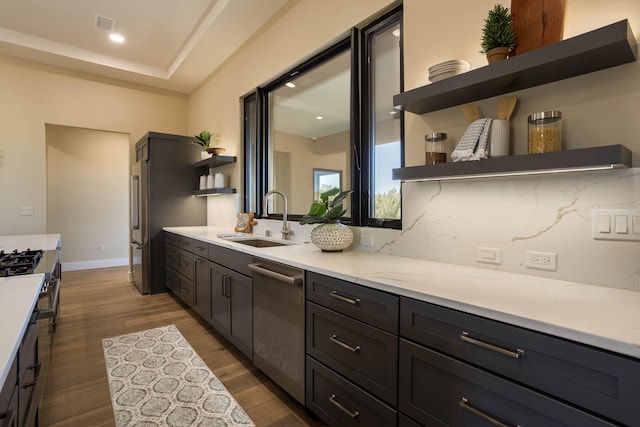 kitchen with light stone counters, dark hardwood / wood-style floors, tasteful backsplash, sink, and stainless steel dishwasher