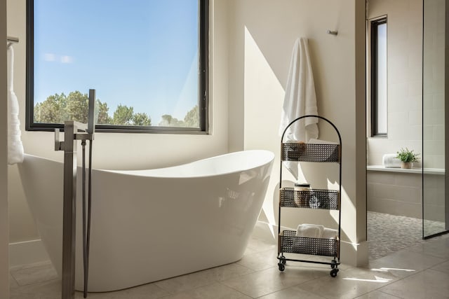 bathroom with a bath, plenty of natural light, and tile patterned floors