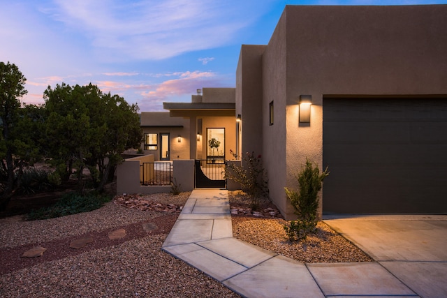 exterior entry at dusk with a porch and a garage