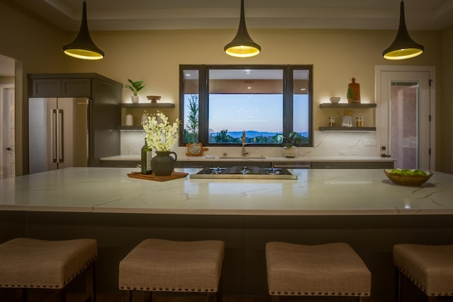 kitchen featuring appliances with stainless steel finishes, hanging light fixtures, light stone counters, a kitchen bar, and sink