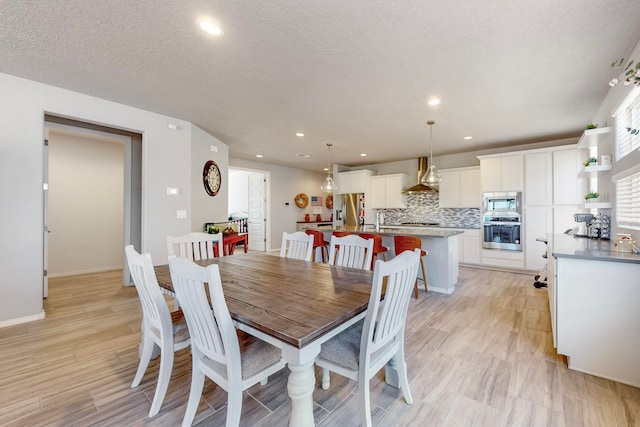 dining space featuring a textured ceiling, sink, and light wood-type flooring