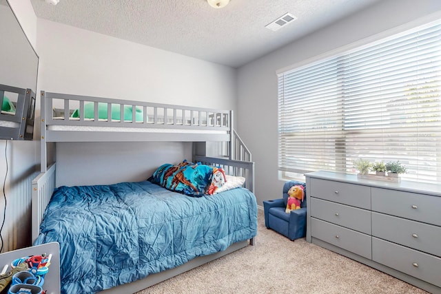 bedroom featuring a textured ceiling and light colored carpet