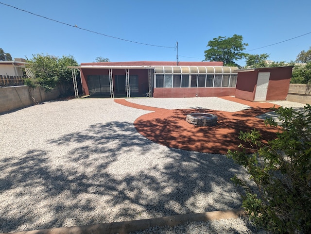 rear view of house with a patio, a sunroom, and an outdoor fire pit