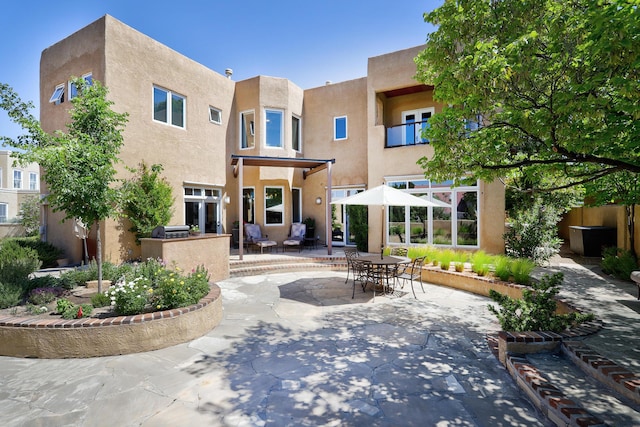 back of property with stucco siding and a patio area