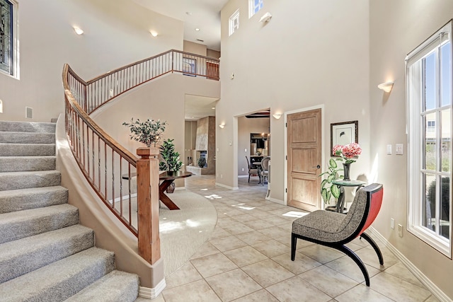 foyer with baseboards, a high ceiling, light tile patterned flooring, and stairs