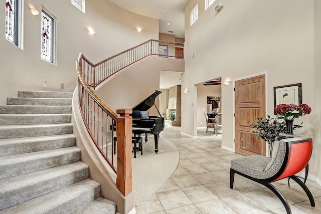 stairway with tile patterned floors, baseboards, and a towering ceiling