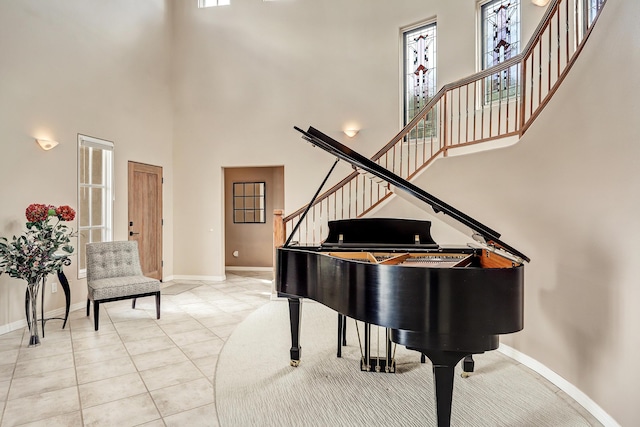 living area featuring light tile patterned floors, stairway, baseboards, and a high ceiling