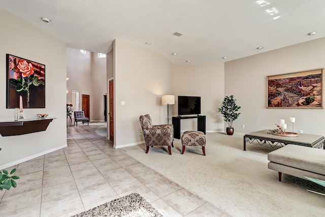 living area with a high ceiling, light tile patterned flooring, light colored carpet, and baseboards