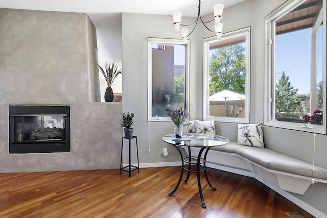 sitting room featuring a multi sided fireplace, baseboards, an inviting chandelier, and wood finished floors