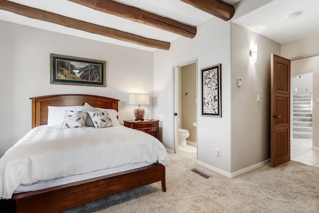 bedroom featuring beam ceiling, connected bathroom, baseboards, and light carpet