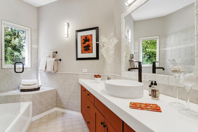 bathroom featuring vanity, a tub to relax in, wainscoting, tile walls, and tile patterned floors