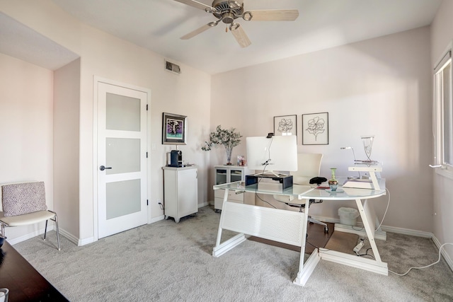 office space with light carpet, visible vents, baseboards, and a ceiling fan