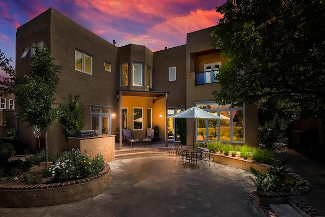 back of house featuring a patio area, an outdoor kitchen, and stucco siding