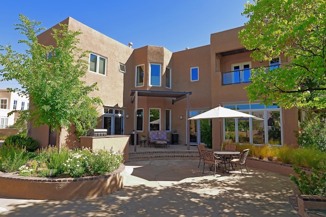 back of house with stucco siding and a patio