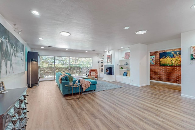 unfurnished living room featuring light wood-type flooring, brick wall, and built in features