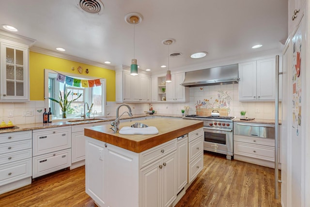 kitchen with luxury stove, wall chimney range hood, sink, and white cabinets