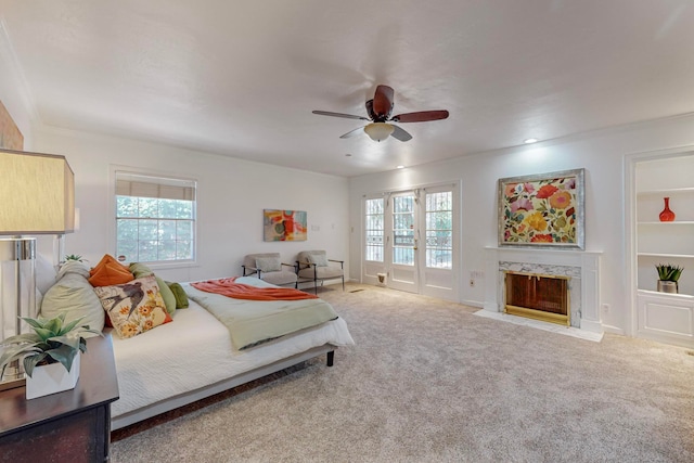 bedroom featuring a premium fireplace, ceiling fan, multiple windows, and access to outside