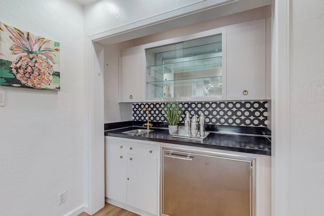 bar featuring decorative backsplash, white cabinetry, light hardwood / wood-style flooring, and sink