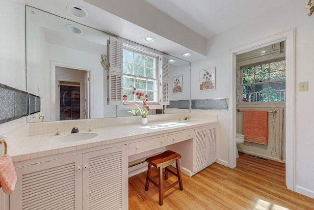 bathroom with hardwood / wood-style flooring, plenty of natural light, vanity, and toilet