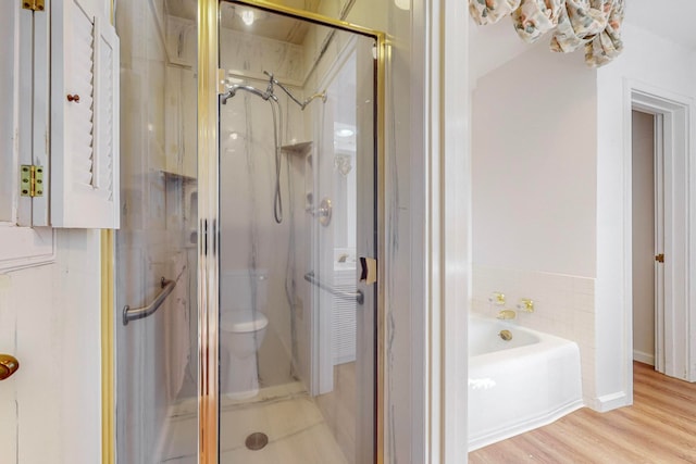 bathroom with wood-type flooring, separate shower and tub, and toilet