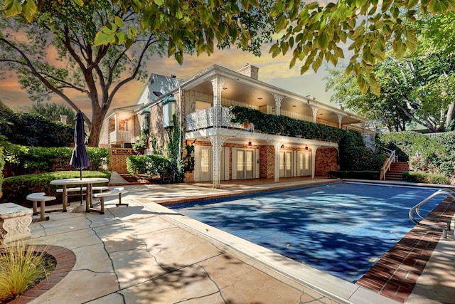 pool at dusk featuring a patio area