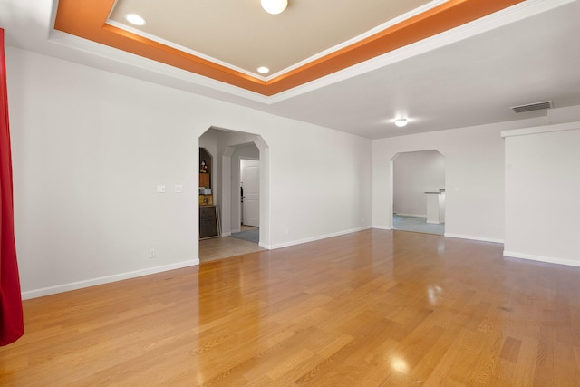 empty room with light hardwood / wood-style floors and a tray ceiling