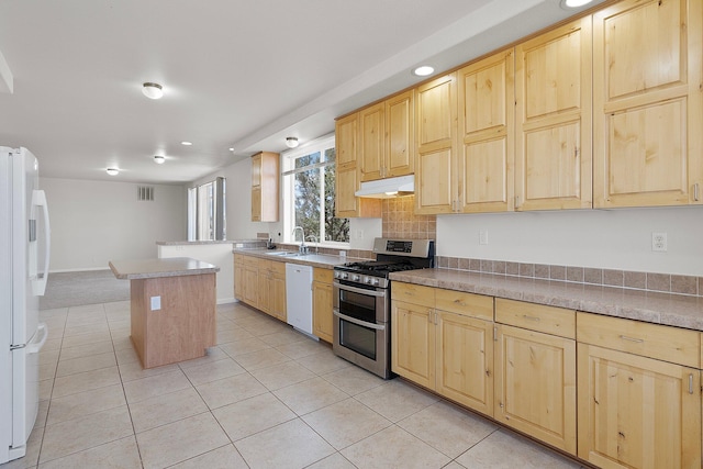 kitchen featuring light brown cabinetry, light tile patterned flooring, sink, a center island, and white appliances