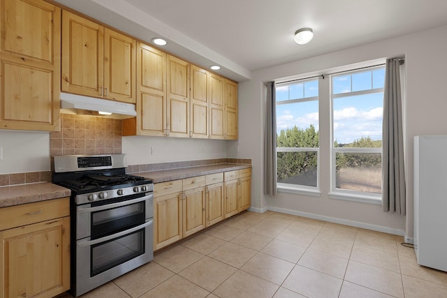 kitchen with light brown cabinetry, gas stove, and light tile patterned floors