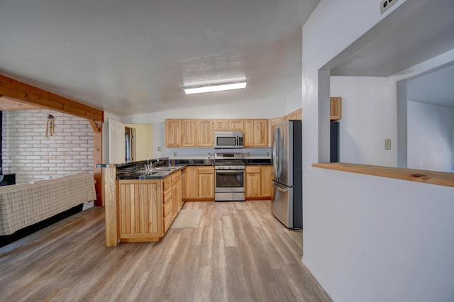 kitchen with light hardwood / wood-style floors, vaulted ceiling, kitchen peninsula, appliances with stainless steel finishes, and light brown cabinetry