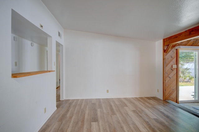 unfurnished living room with light hardwood / wood-style floors and wood walls