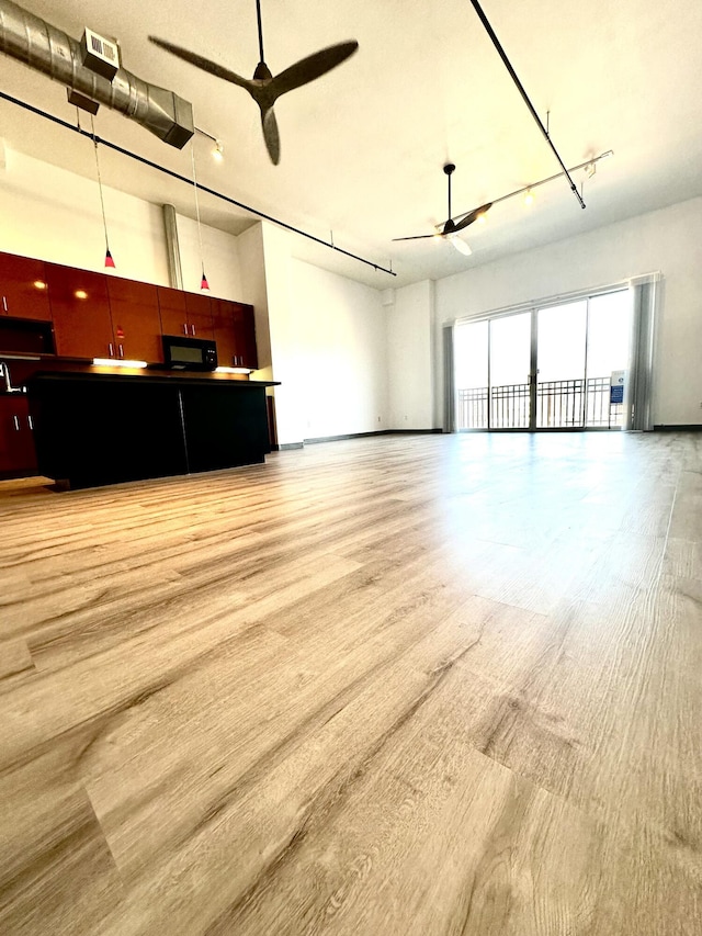 unfurnished living room with visible vents, track lighting, a ceiling fan, and light wood-style floors