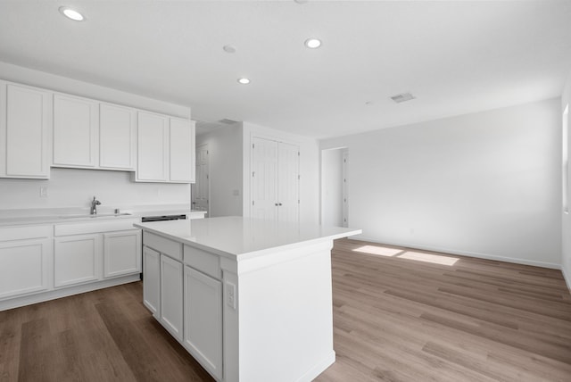 kitchen with a kitchen island, light countertops, light wood-style floors, white cabinetry, and a sink