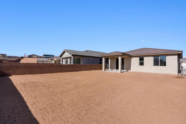 rear view of house with stucco siding and fence