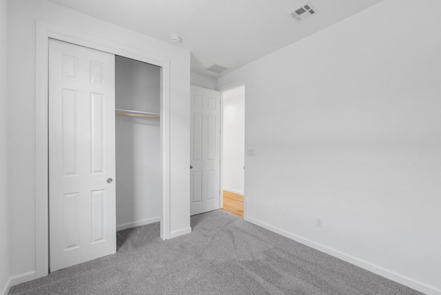 unfurnished bedroom featuring carpet, visible vents, a closet, and baseboards