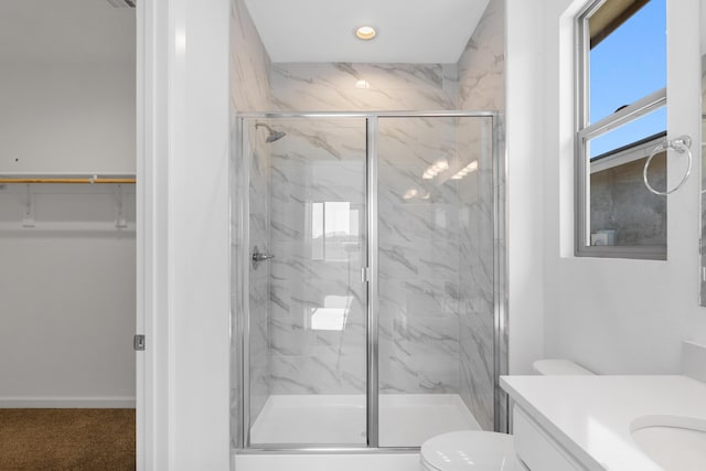 bathroom with a marble finish shower, toilet, vanity, and a walk in closet