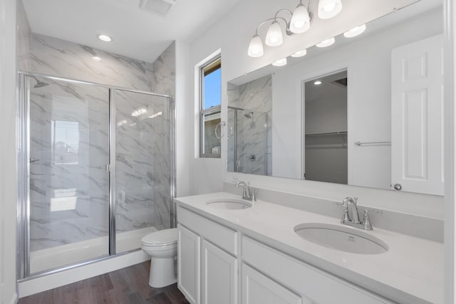 bathroom featuring a marble finish shower and a sink