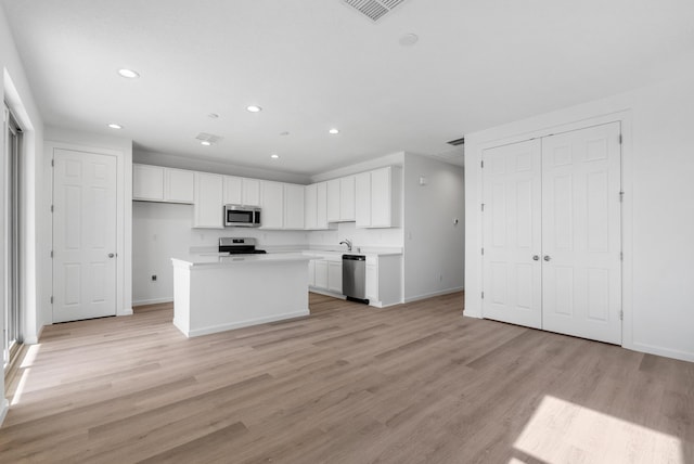 kitchen with visible vents, light wood-style flooring, stainless steel appliances, light countertops, and white cabinetry